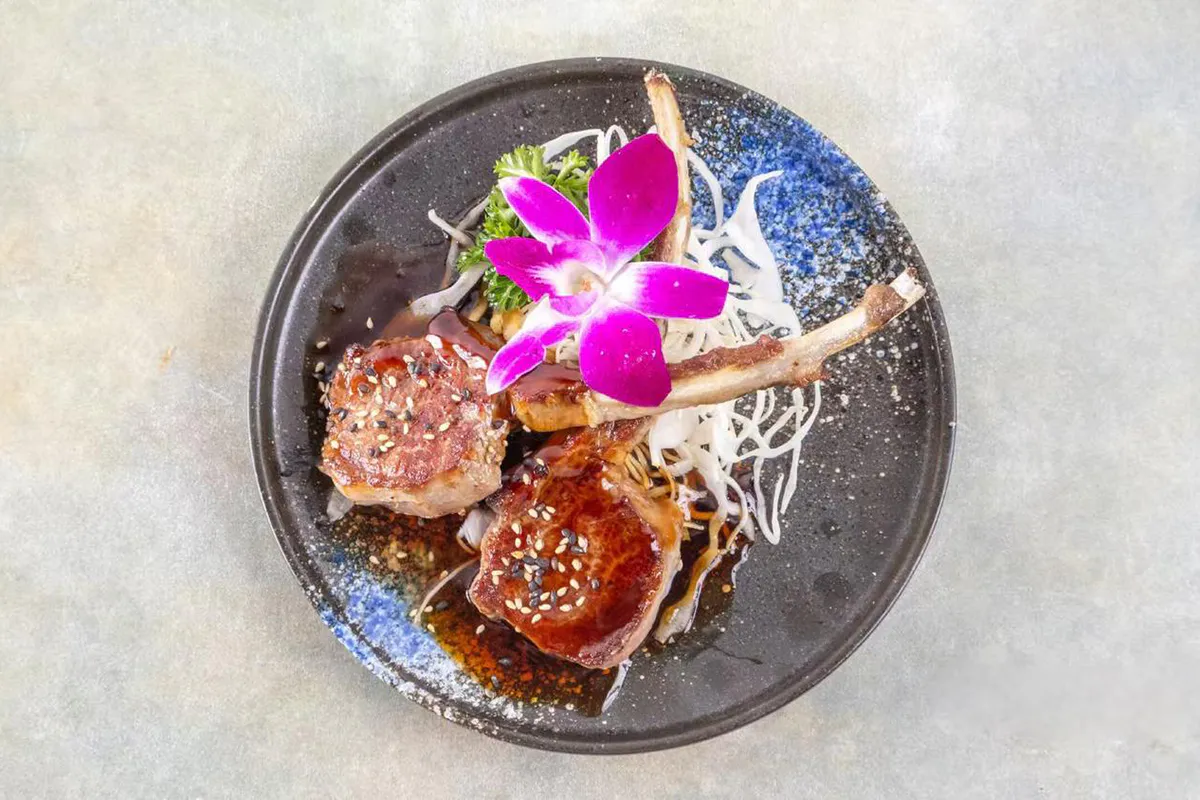 Glazed lamb chops with sesame and orchid garnish at Wabi Wok & Ramen, an Asian Restaurant in Milford