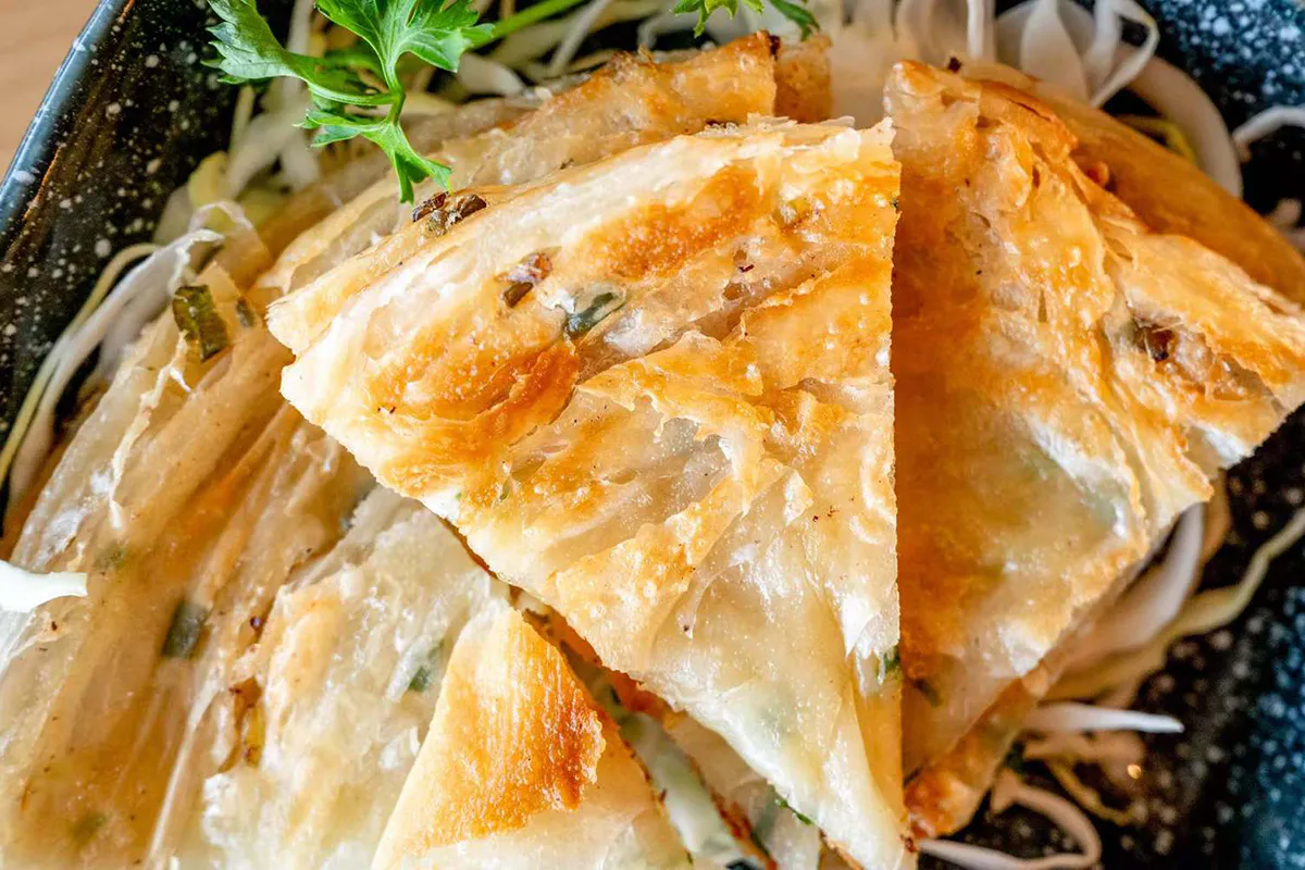 Crispy scallion pancakes cut into golden wedges at Wabi Wok & Ramen, an Asian Restaurant in Milford